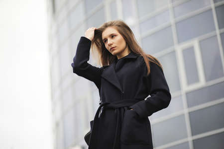 Beautiful girl in a coat in business downtownの写真素材