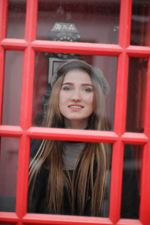 Beautiful young girl in a phone booth. The girl is talking on th