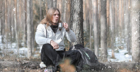 A man in a campaign drinks tea. A young traveler in the woods caの写真素材