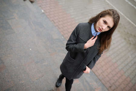 Young adult girl in coat on the streetの写真素材