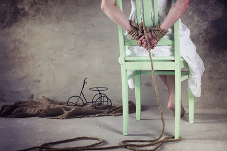 Young girl tied up on the floor. The abducted girl. The victim of violence sits on floor with tied...
