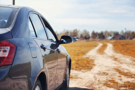 The car is parked in the field. The car is driving along the rural road to the house. The car is gray in the meadow in front of country road
の写真素材