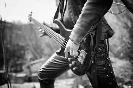Rock guitarist on the steps. A musician with a bass guitar in a leather suit. Metalist with a guitar on the background of industrial step.
の写真素材