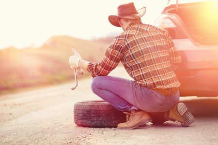 Man is sitting on the road by the car