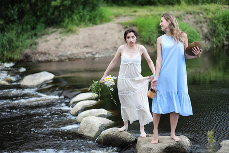 Beautiful girls in dresses on the river
