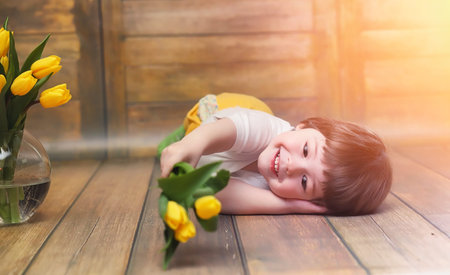 A small child with a bouquet of yellow tulips. A boy with a gift