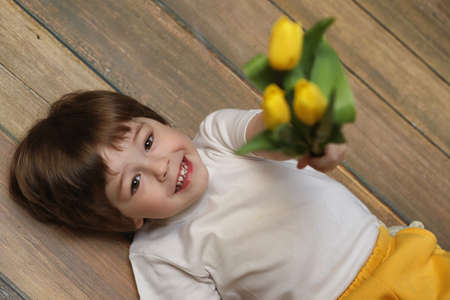 A small child with a bouquet of yellow tulips. A boy with a giftの写真素材