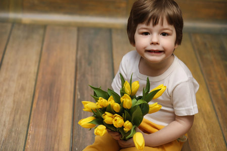 A small child with a bouquet of yellow tulips. A boy with a gift