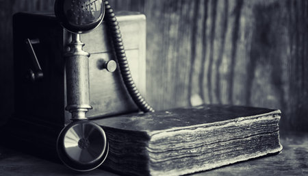 Old telephone and retro book on the desk. The phone of the past
