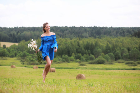 Young cute girl run in a field at sunsetの写真素材