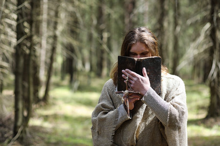 A man in a cassock spends a ritual in a dark forestの写真素材