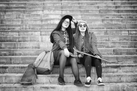 A young hipster girl is riding a skateboard. Girls girlfriends f