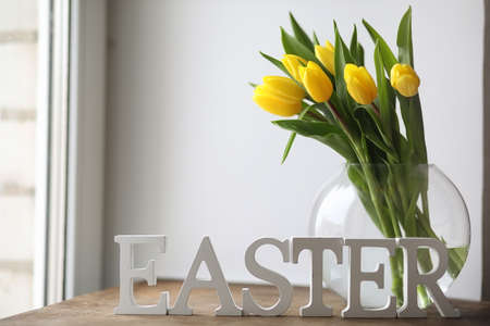 A bouquet of yellow tulips in a vase on the windowsill. A gift tの写真素材