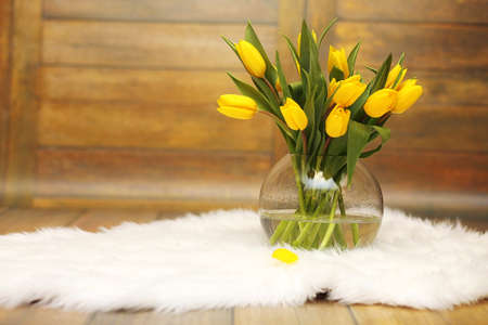 A bouquet of yellow tulips in a vase on the floor. A gift to a wの写真素材