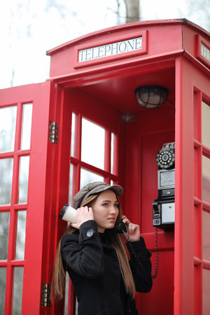 Beautiful young girl in a phone booth. The girl is talking on thの写真素材