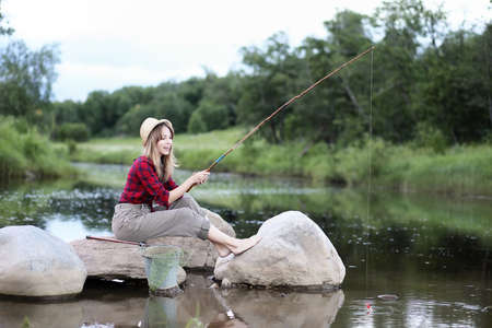 Girl by the river with a fishing rodの写真素材