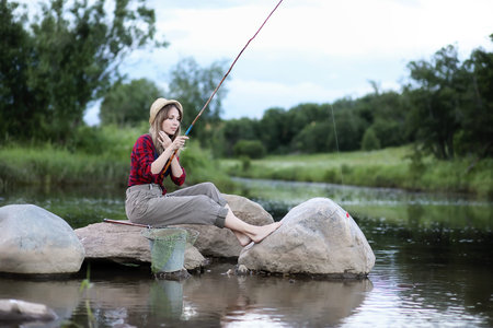 Girl by the river with a fishing rodの写真素材