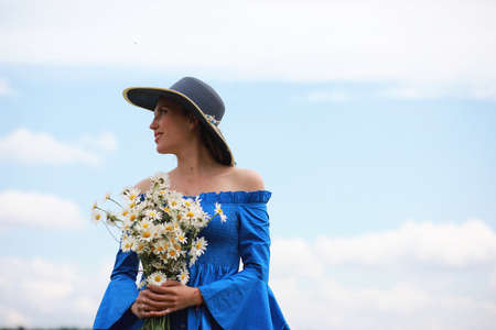 Young cute girl in a hat in a field at sunsetの写真素材