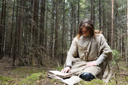 A man in a cassock spends a ritual in a dark forestの写真素材