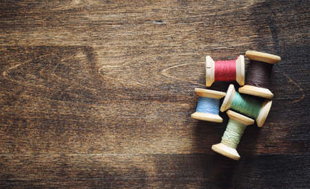Sewing thread on a wooden background. Set of threads on bobbinsの写真素材