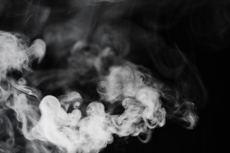 White smoke on a black background. Texture of smoke. Clubs of white smoke on a dark background for overlayの写真素材