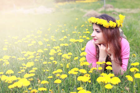 girl resting on a sunny day in meadow of yellow dandelionsの写真素材