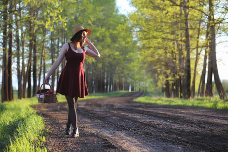A girl in a hat on a walk in the park. A girl with a basket walkの写真素材
