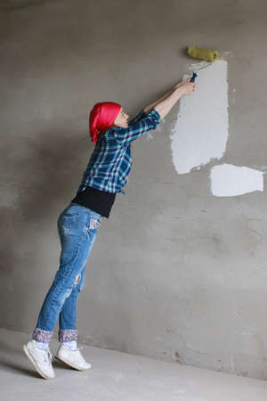 The girl is doing repairs in the apartment. Home moving to a new apartment. The worker makes repairs, plastered and drills the wall.の写真素材