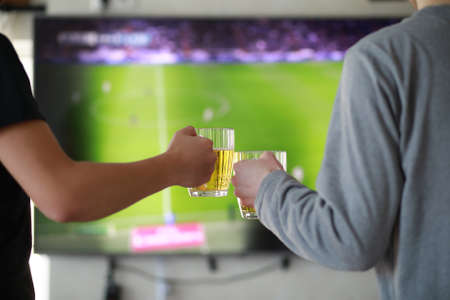 Football fans watch the match and drink beer indoorの写真素材