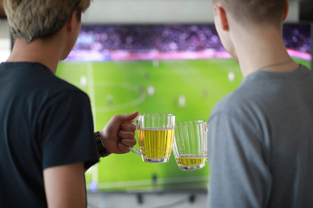 Football fans watch the match and drink beer indoorの写真素材