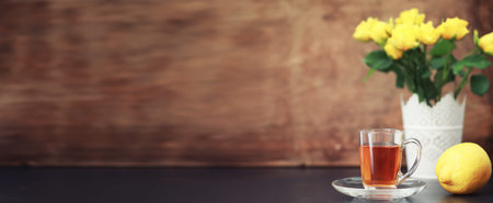 A cup with tea on the table and flowers in a vase