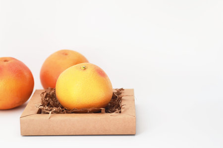 Fresh juicy grapefruits on a white table in a small basket