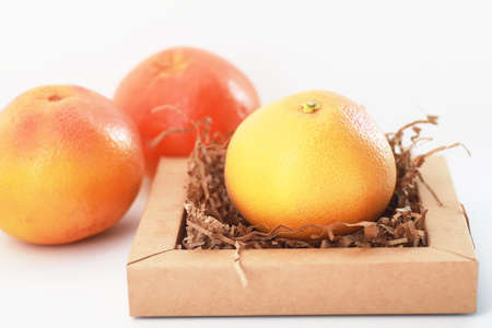 Fresh juicy grapefruits on a white table in a small basketの写真素材