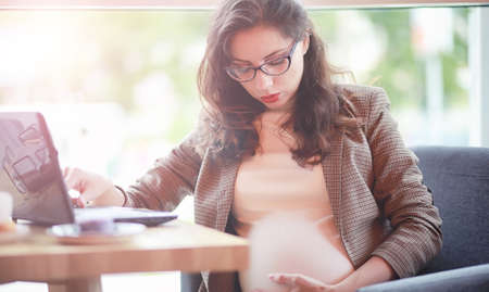 Pregnant woman working during lunch on computer in cafeの写真素材