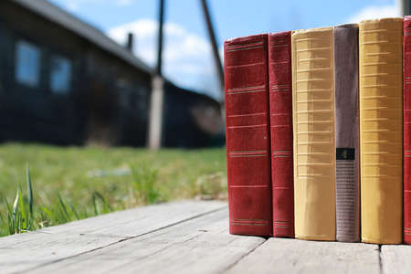 books standing different objects on a wooden table on a background of blurred summer foliageの写真素材