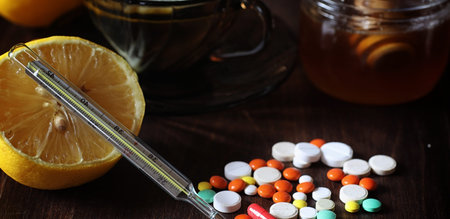 Drugs and pills on a wooden table. Various means to prevent colds. Tea with lemon and honey. Glass cup with tea slice of lemon and a jar of honey.の写真素材