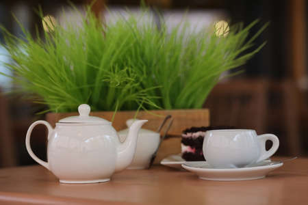 Kettle with a drink and dessert in street cafe. Tea in the kettle cup on the table. Breakfast with tea and cakes at the cafe.の写真素材