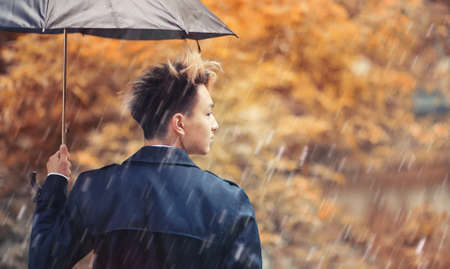 Autumn rainy weather and a young man with an umbrellaの写真素材