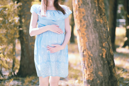 Pregnant girl in a dress in nature on a walk