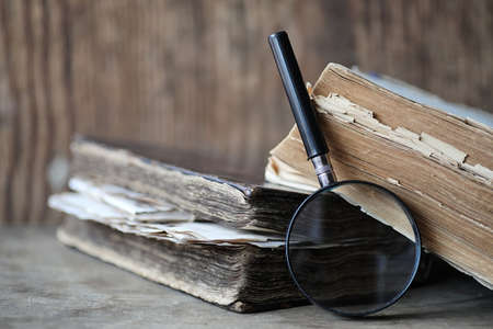 Old books on a wooden table and glass magnifierの写真素材