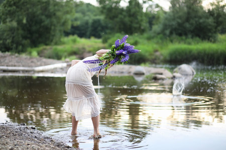 Beautiful girl with a bouquet of blue flowers on nature in summerの写真素材