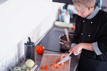 Asian cook in the kitchen prepares food in a cook suit