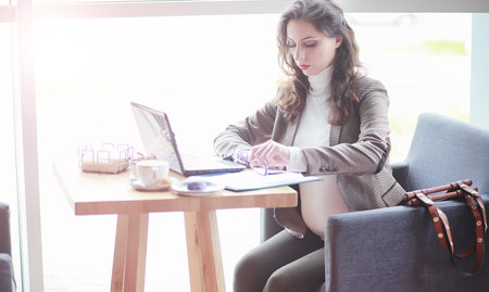 Pregnant woman working on computer in cafe