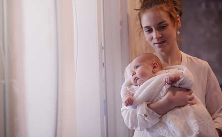 Mom with a newborn baby in her arms. The girl is holding a babyの写真素材