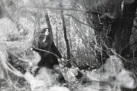 Woman in a witch suit in a dense forest