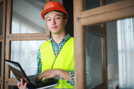 Asian man in protective helmet and construction waistcoat