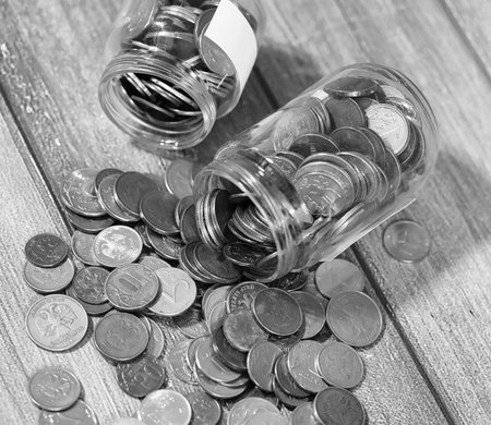 Coins in a jar on the floor. Accumulated coins on the floor. Pocket savings in piles.の写真素材