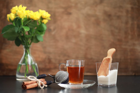 A cup with tea on the table and flowers in a vase