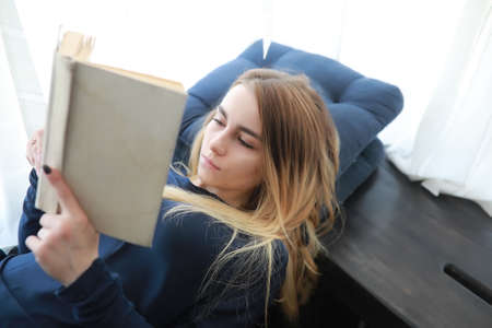 Young girl reading a book and relaxing at home.の写真素材