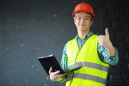 Asian man in protective helmet and construction waistcoatの写真素材